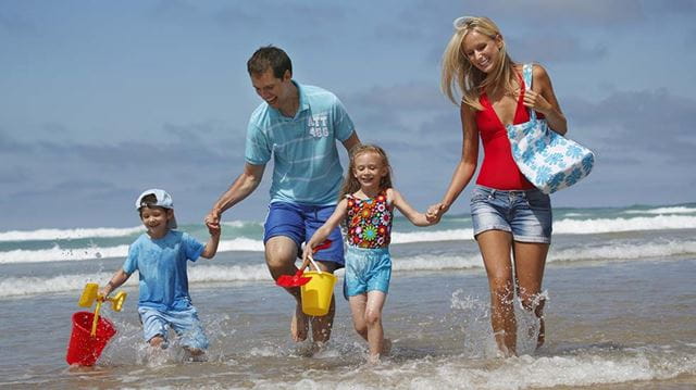 October half-term holiday advice family walking on beach